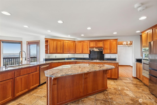 kitchen featuring stainless steel appliances, a center island, sink, and light stone countertops