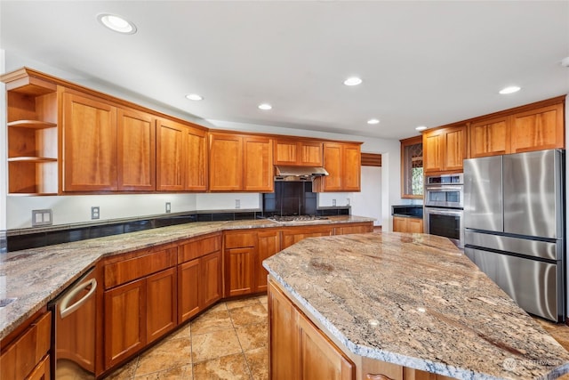 kitchen with a kitchen island, appliances with stainless steel finishes, and light stone counters