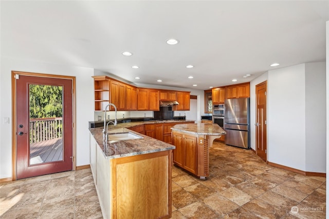 kitchen featuring sink, appliances with stainless steel finishes, a kitchen breakfast bar, a kitchen island, and stone counters