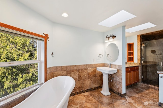 bathroom featuring tile walls, a skylight, and independent shower and bath