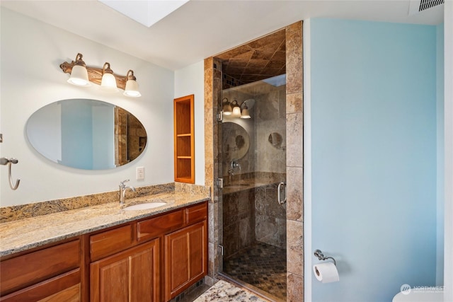 bathroom featuring vanity, an enclosed shower, and a skylight