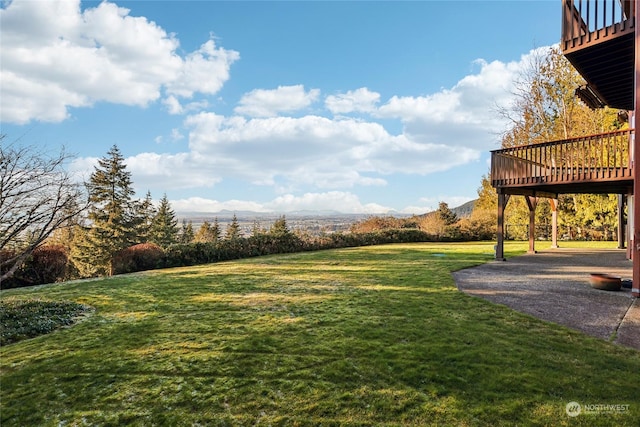 view of yard featuring a deck with mountain view and a patio area