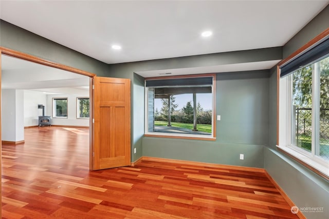 unfurnished room with a wood stove and light hardwood / wood-style floors