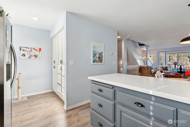 kitchen with stainless steel refrigerator with ice dispenser, gray cabinets, and light wood-type flooring