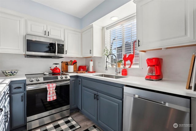 kitchen with white cabinetry, stainless steel appliances, sink, and wood-type flooring