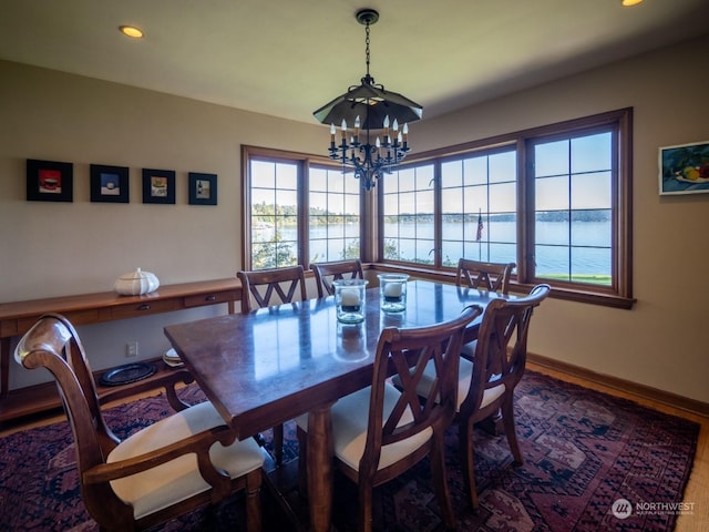 dining space with a water view, hardwood / wood-style floors, and an inviting chandelier