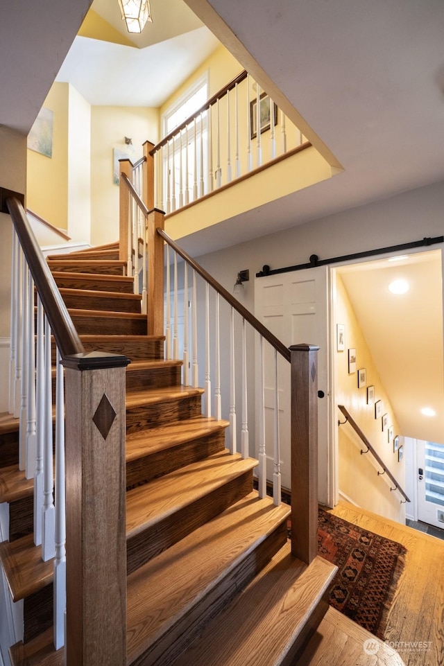 stairway with hardwood / wood-style flooring and a barn door