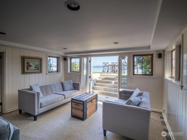 carpeted living room featuring wood walls