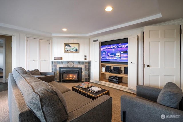 living room with a tiled fireplace and a tray ceiling