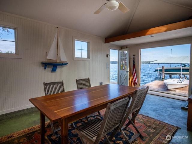 carpeted dining area with a water view and ceiling fan