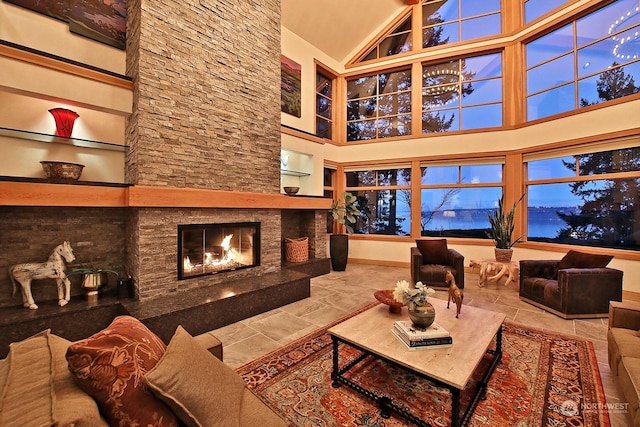 living room with a stone fireplace and high vaulted ceiling