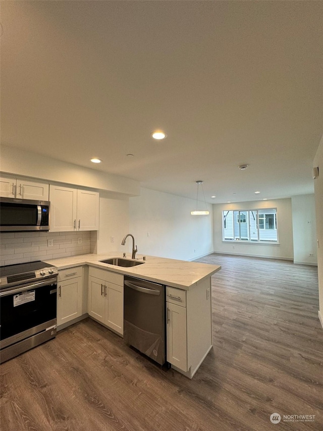 kitchen featuring pendant lighting, sink, stainless steel appliances, dark hardwood / wood-style floors, and white cabinets