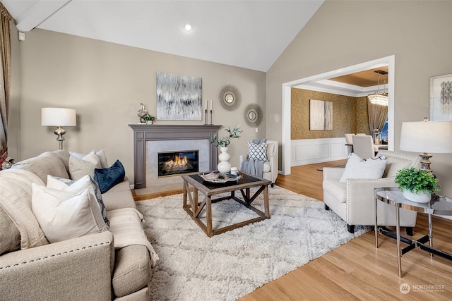 living room with a tiled fireplace, wood-type flooring, and vaulted ceiling