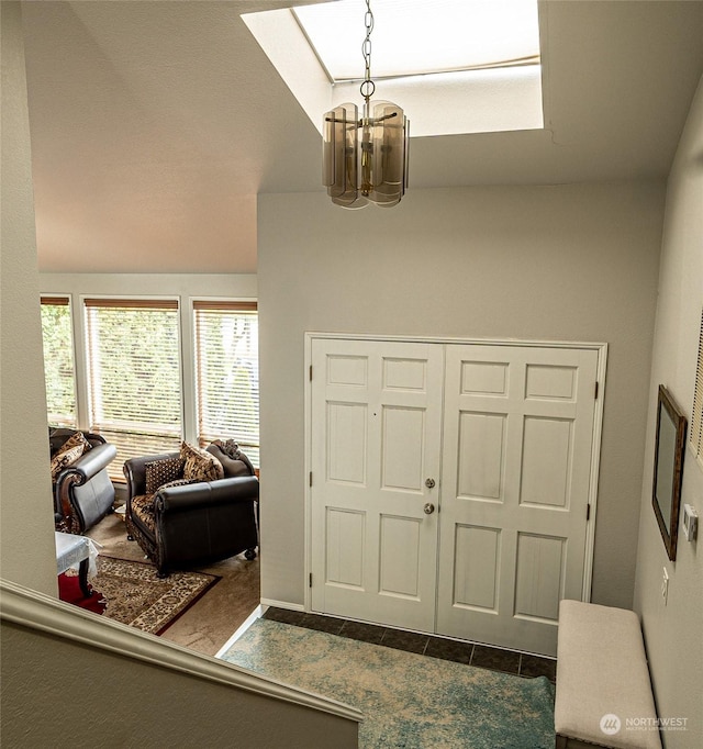 foyer entrance featuring lofted ceiling, dark tile patterned flooring, and an inviting chandelier