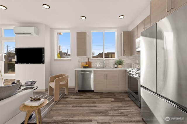 kitchen with stainless steel appliances, a sink, an AC wall unit, light countertops, and tasteful backsplash