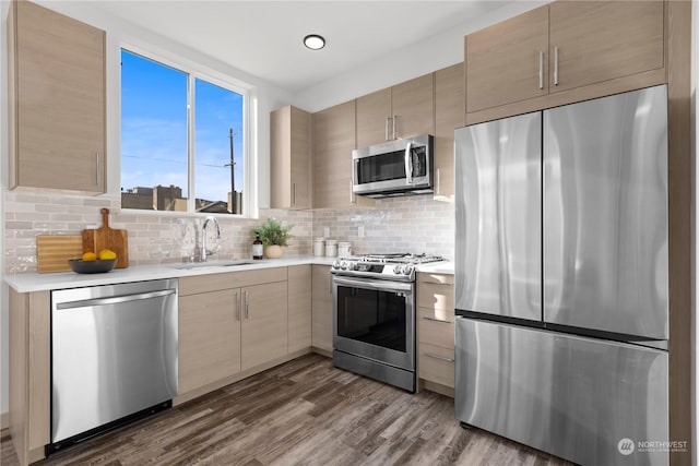 kitchen featuring appliances with stainless steel finishes, dark wood-style flooring, a sink, light countertops, and backsplash