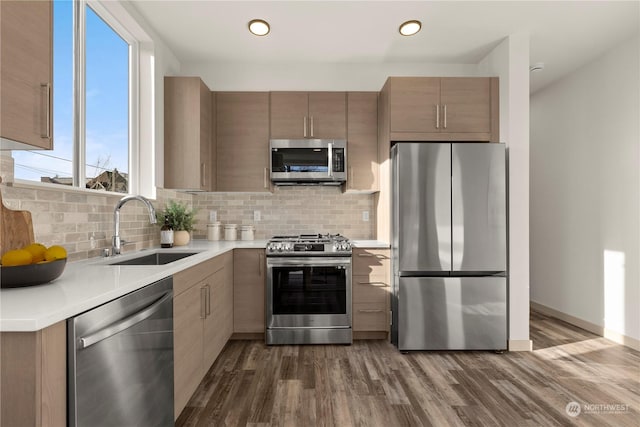 kitchen featuring decorative backsplash, dark wood-style flooring, stainless steel appliances, light countertops, and a sink