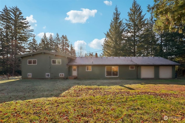 back of property with a garage and a lawn