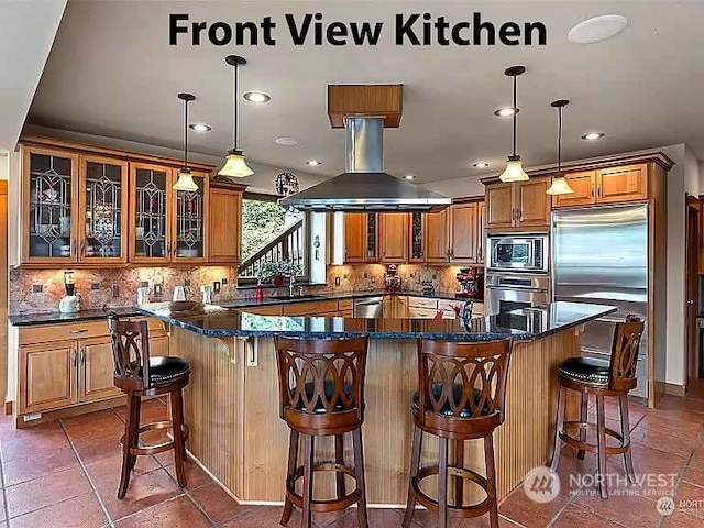 kitchen with pendant lighting, island range hood, built in appliances, and decorative backsplash