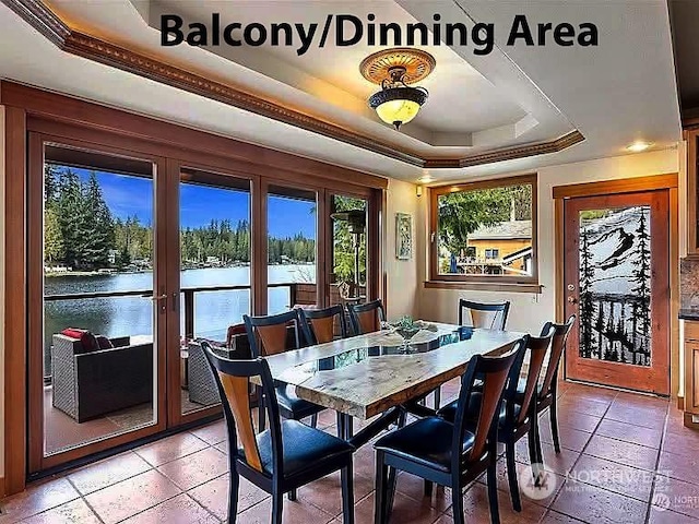 dining space featuring a water view, ornamental molding, and a tray ceiling