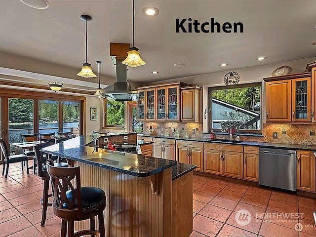 kitchen featuring dishwasher, sink, backsplash, a kitchen breakfast bar, and island exhaust hood