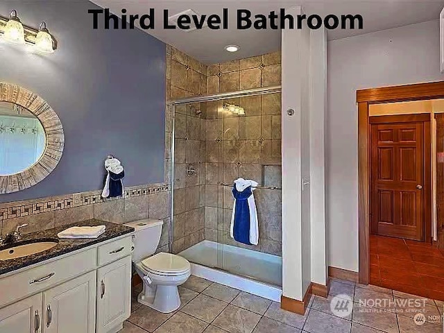 bathroom with a shower with door, tile patterned floors, and toilet