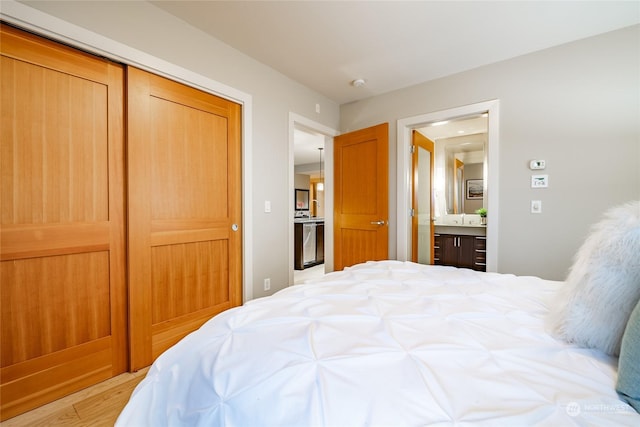 bedroom with ensuite bathroom, light wood-type flooring, and a closet