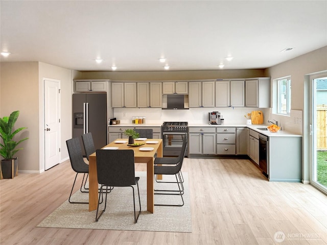 kitchen featuring black gas stove, fridge with ice dispenser, gray cabinets, light wood-style flooring, and stainless steel dishwasher