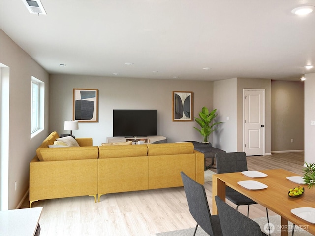 living area featuring light wood finished floors, visible vents, and baseboards