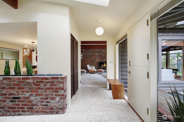 hallway featuring vaulted ceiling and brick wall