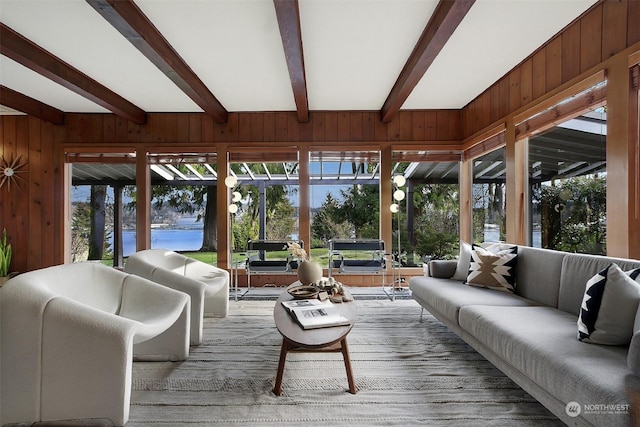 sunroom with beamed ceiling and a water view