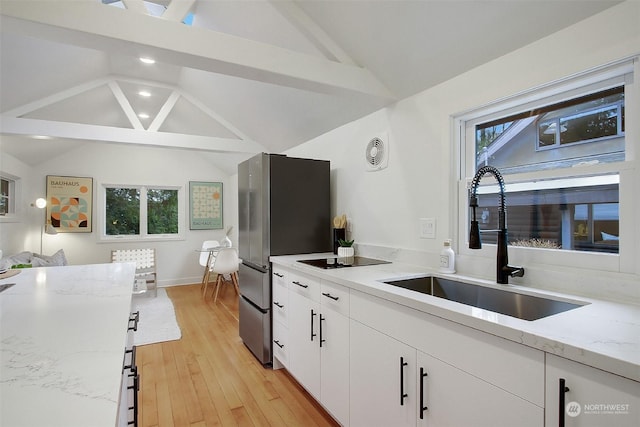 kitchen featuring white cabinetry, lofted ceiling, sink, and light stone counters