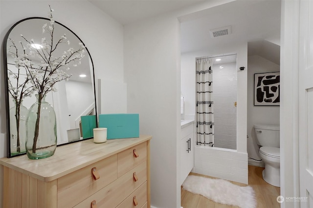 full bathroom featuring hardwood / wood-style flooring, vanity, shower / bathtub combination with curtain, and toilet