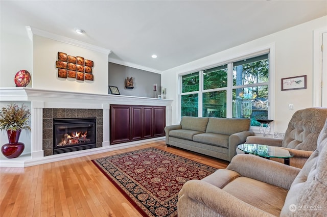 living room with light hardwood / wood-style flooring, a fireplace, and ornamental molding