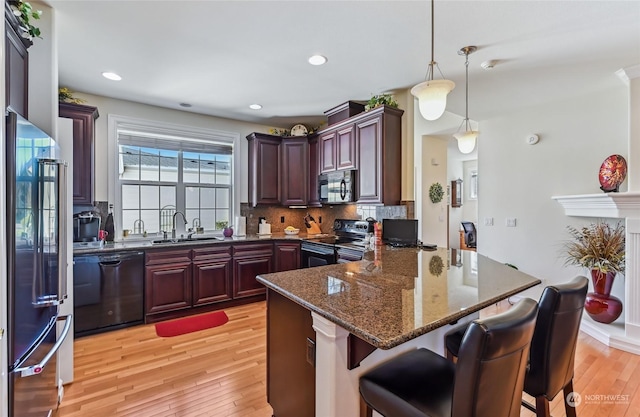 kitchen featuring sink, hanging light fixtures, dark stone countertops, decorative backsplash, and black appliances