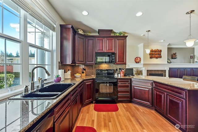 kitchen featuring sink, hanging light fixtures, tasteful backsplash, light stone counters, and black appliances