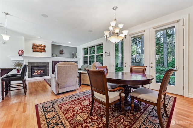 dining area featuring a tile fireplace, a chandelier, and light wood-type flooring