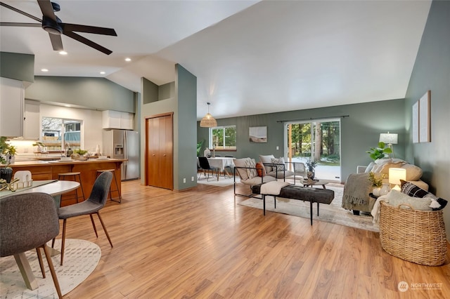 living room with ceiling fan, high vaulted ceiling, and light wood-type flooring