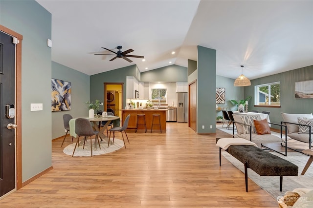 living room with washer / clothes dryer, vaulted ceiling, ceiling fan, and light hardwood / wood-style flooring