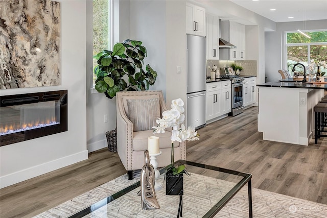 interior space featuring tasteful backsplash, dark countertops, appliances with stainless steel finishes, a sink, and wall chimney exhaust hood