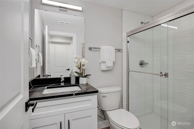 full bathroom featuring visible vents, a shower stall, toilet, and vanity