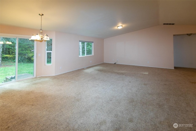 spare room featuring carpet floors and a notable chandelier