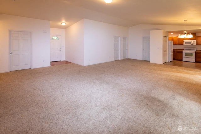 unfurnished living room with lofted ceiling, a chandelier, and carpet floors