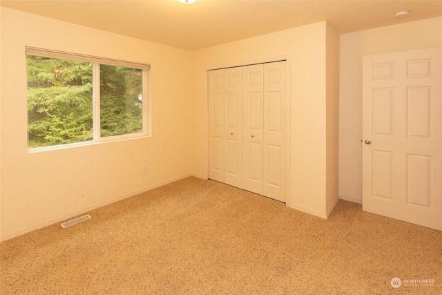 unfurnished bedroom with light colored carpet and a closet