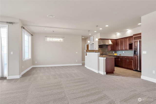 kitchen featuring ventilation hood, light carpet, decorative backsplash, and decorative light fixtures