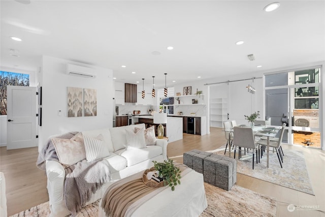 living room featuring a barn door, a wall mounted AC, light hardwood / wood-style floors, and a wealth of natural light