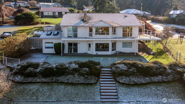 rear view of house featuring a balcony and a lawn