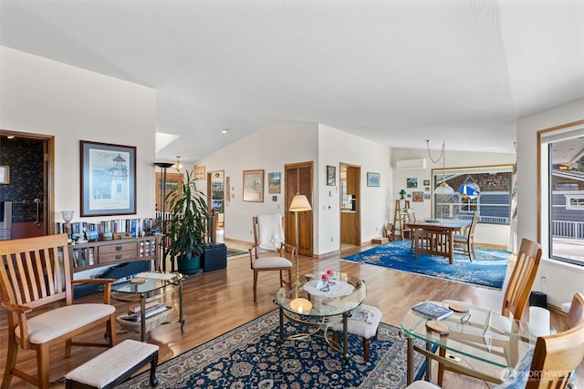 living room featuring a wall mounted AC, lofted ceiling, a textured ceiling, and wood-type flooring