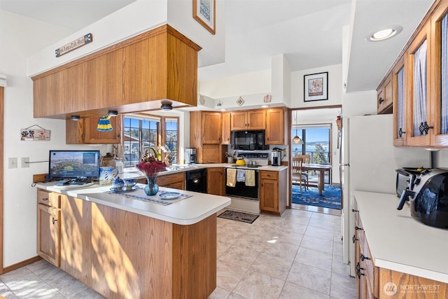 kitchen featuring light tile patterned flooring, plenty of natural light, black appliances, and kitchen peninsula