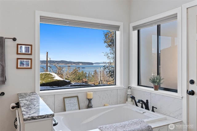 bathroom featuring a water view and a relaxing tiled tub